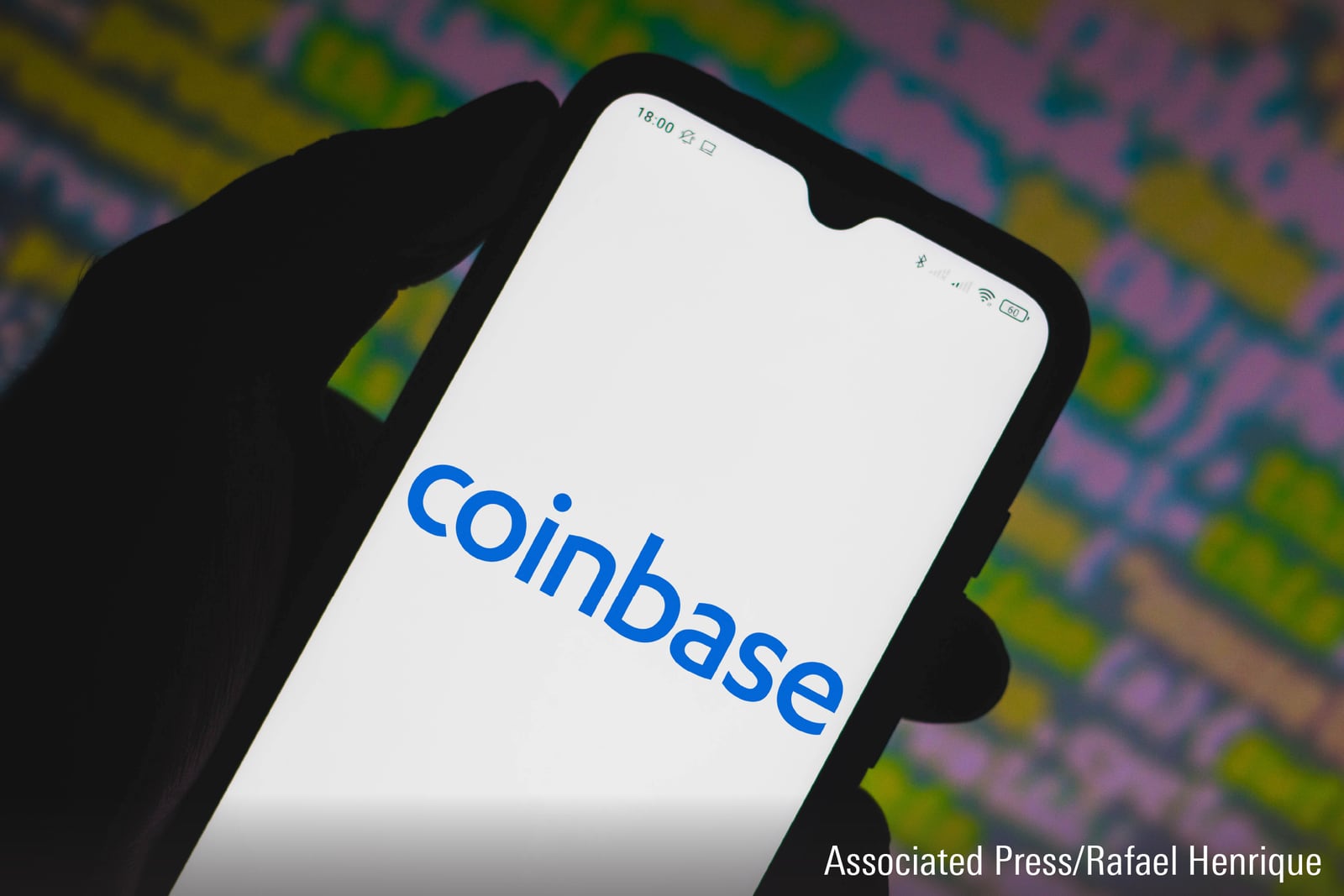 A photograph featuring a Coinbase logo displayed on a smartphone.