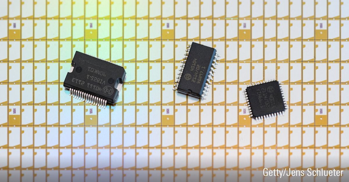 Three semiconductor chips placed in a row on top of a sheet of electronic chips.